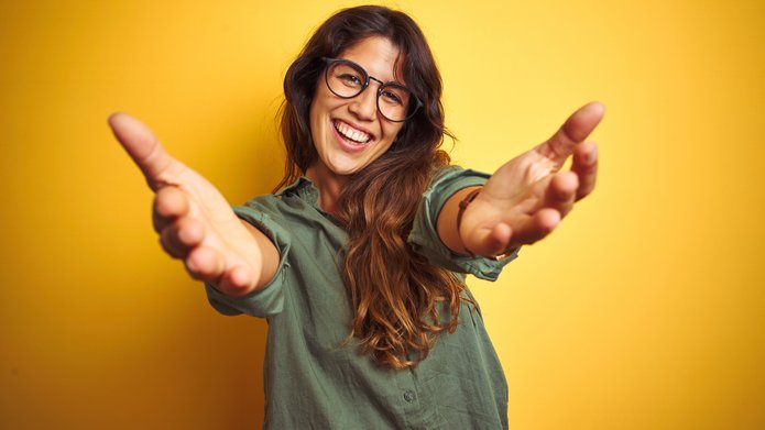 uśmiechnięta młoda kobieta z otwartymi ramionami