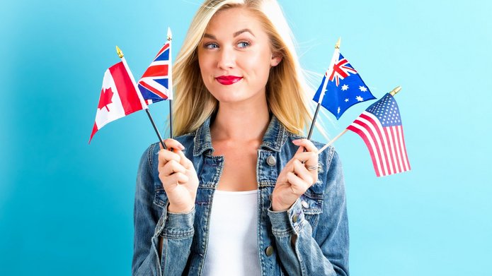 Young smiling woman holding flags of English speaking countries